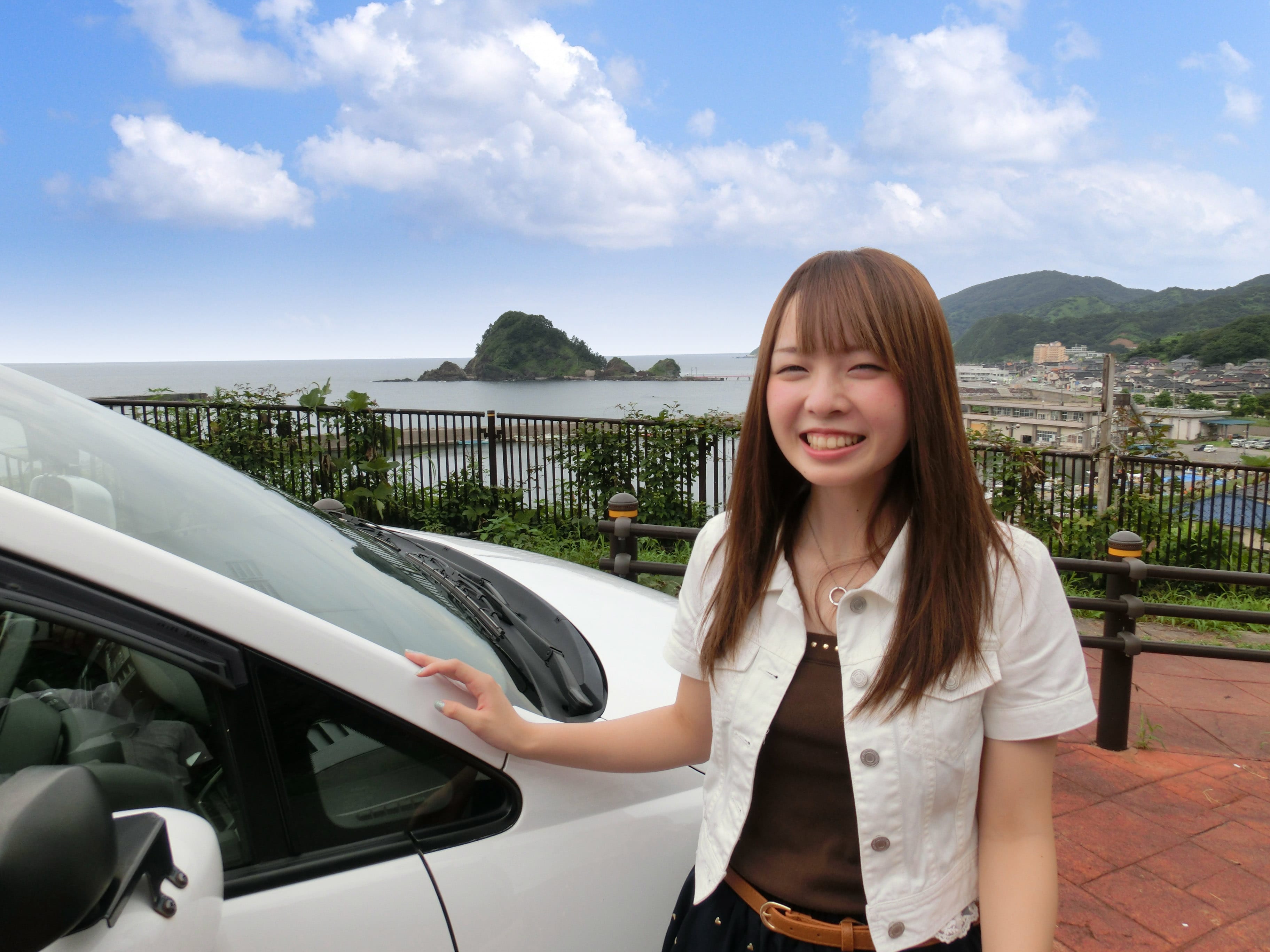 日本海をバックに車と女性